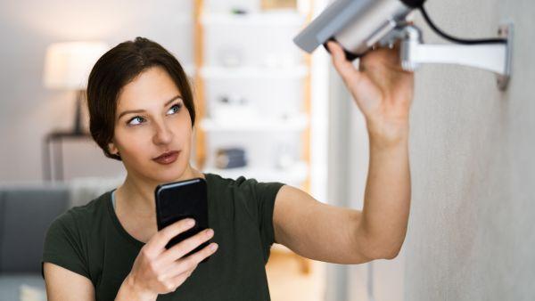 Mulher acessando funções de monitoramento da casa em aplicativo de smartphone