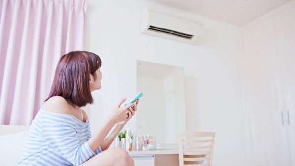 Mulher controlando ar-condicionado inteligente pelo celular