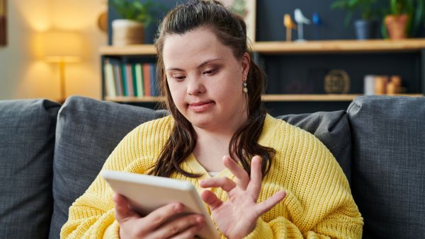 Mulher com síndrome de down controlando dispositivos inteligentes da casa com tablet
